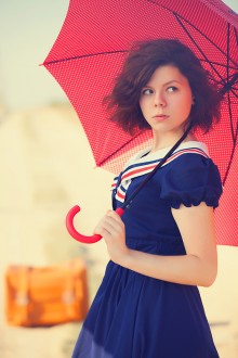Beautiful brunette girl with suitcase and umbrella on the countr